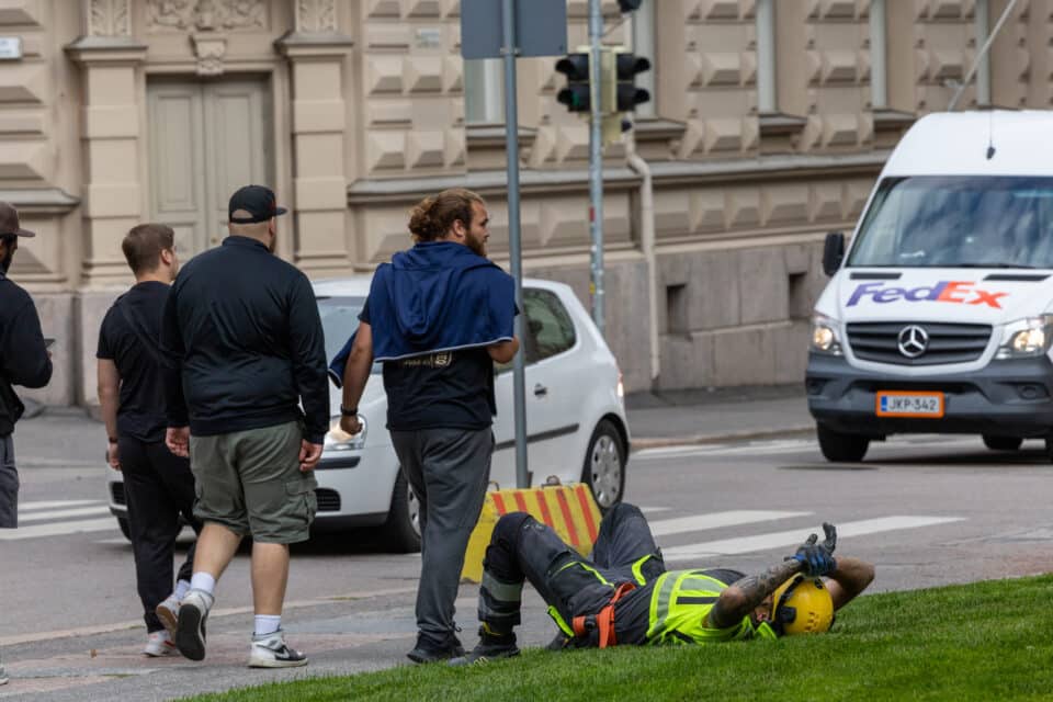 Ehitustööline pikutab puhkepausi ajal Helsingis murul.